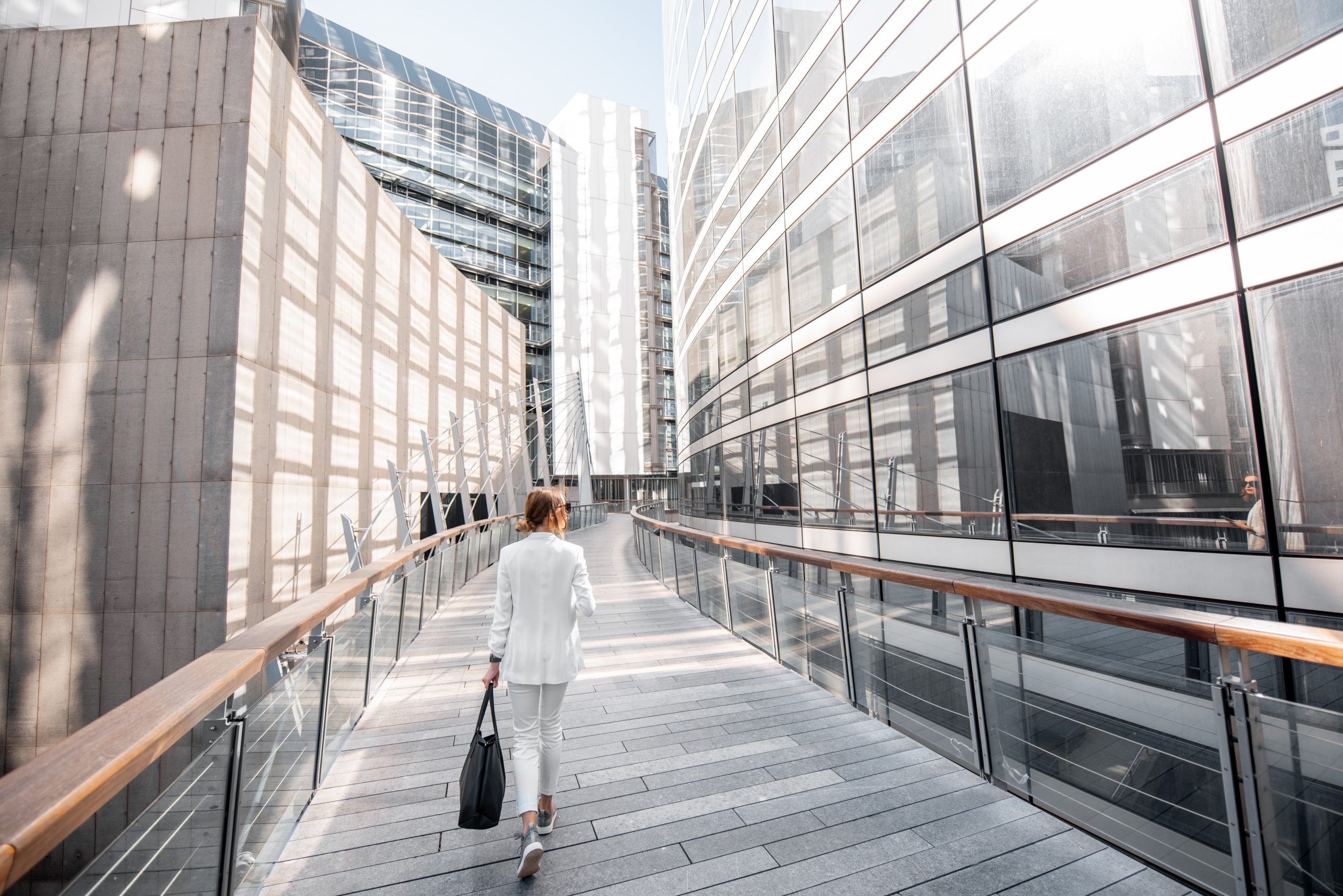 Woman Crossing Bridge Between Corporate Buildings
