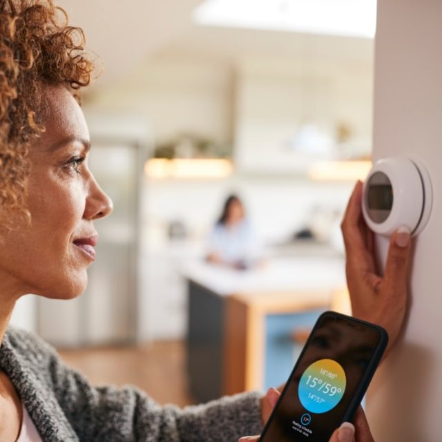 Woman adjusting thermostat